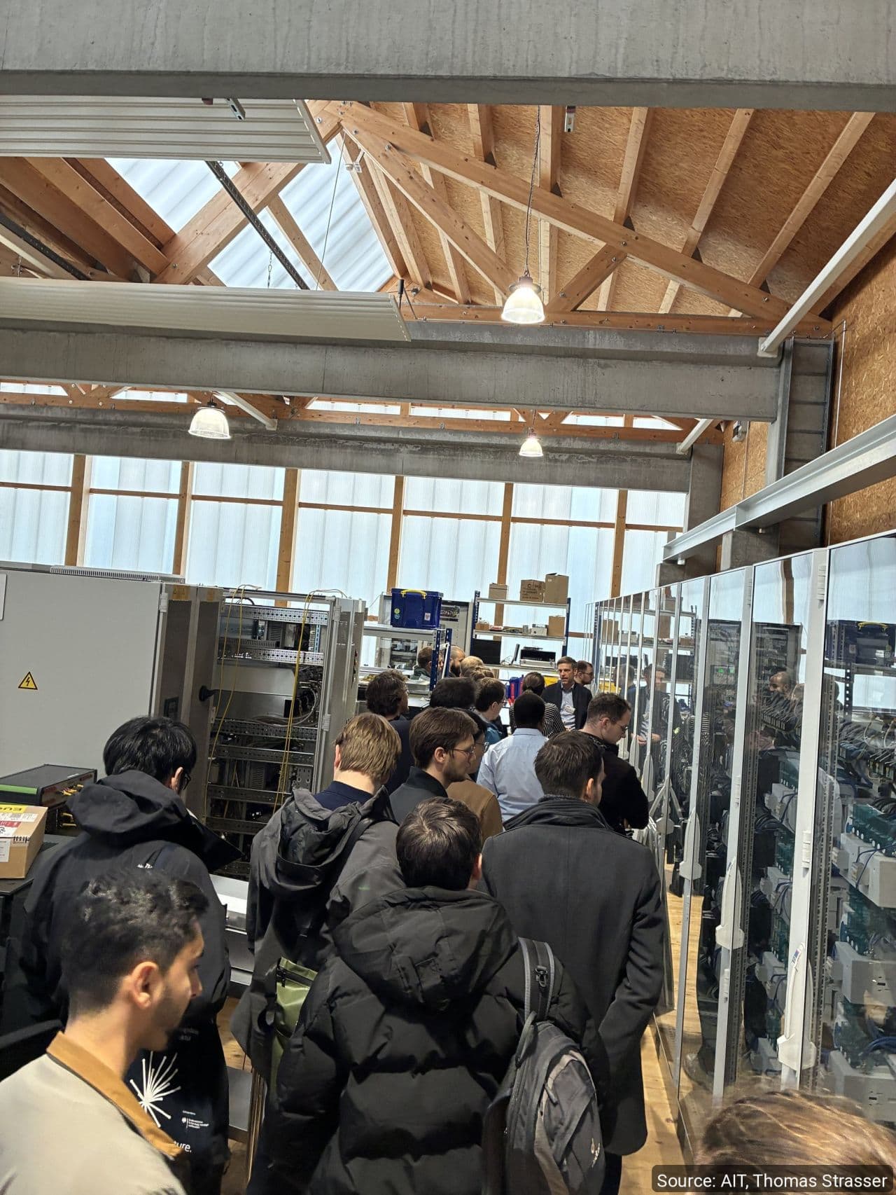 Group of visitors between equipment racks in a laboratory
