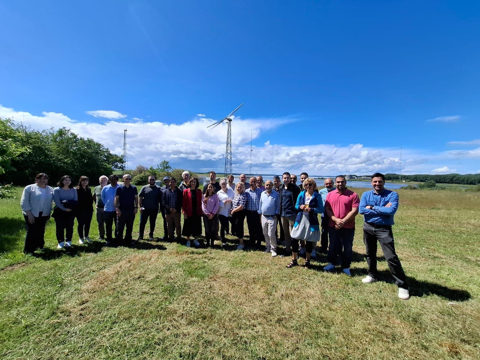 Project consortium standing in a field beside a research wind turbine